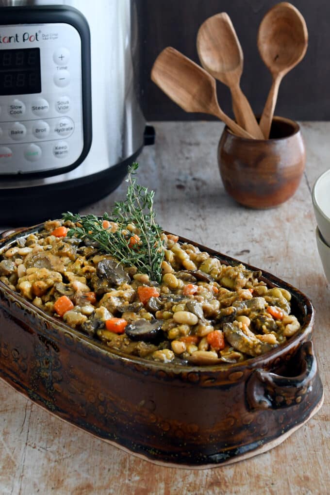 Vegan Cassoulet in a brown oval serving dish, with fresh thyme on top.