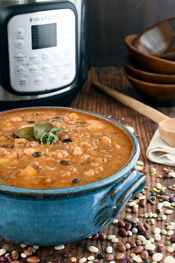 Bean soup in a big blue crock, scattered dry beans on the counter and an instant pot in the background.