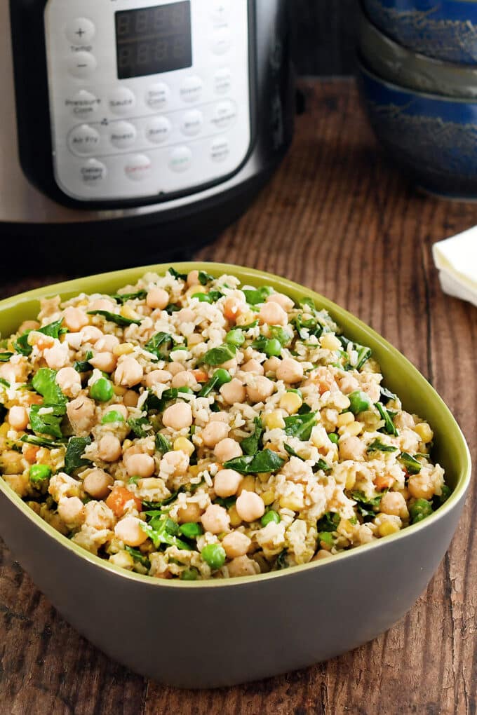 Gray and green serving dish with chickpeas, rice, and veggies. In front of an Instant Pot.