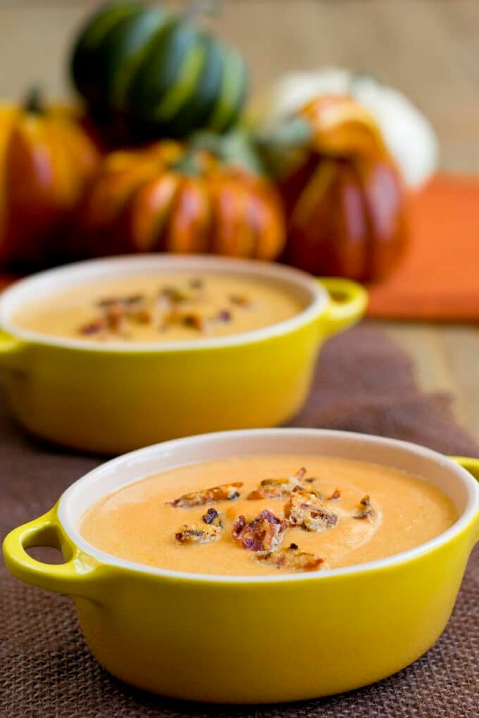 Pumpkin Soup with bacon crumbles on top, in yellow bowls.