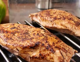 Cooked and seared chicken breasts on a rack in front of a sous vide machine.