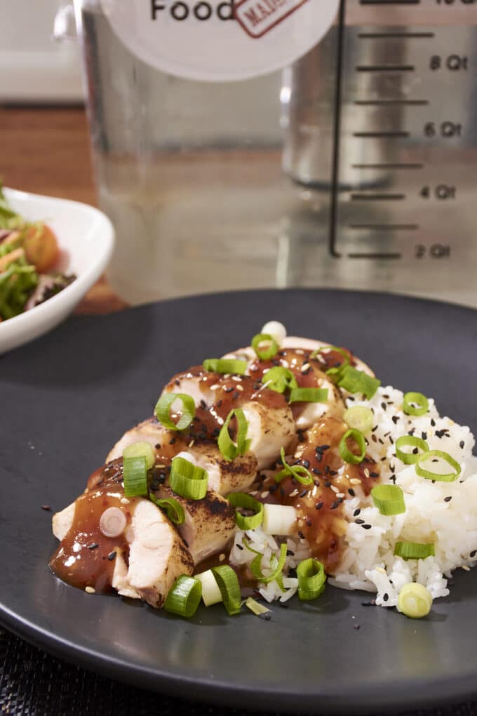 Chinese Garlic Chicken over white rice with green onion and black sesame seeds on top.