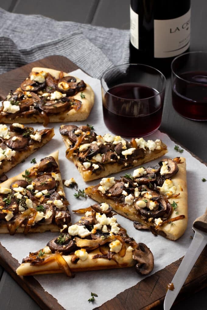 Mushroom Flatbread Mushroom pizza with onions and goat cheese on a wooden board with parchment paper.