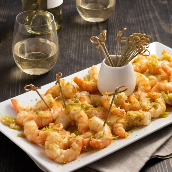 Shrimp scampi on a plate with little skewers.