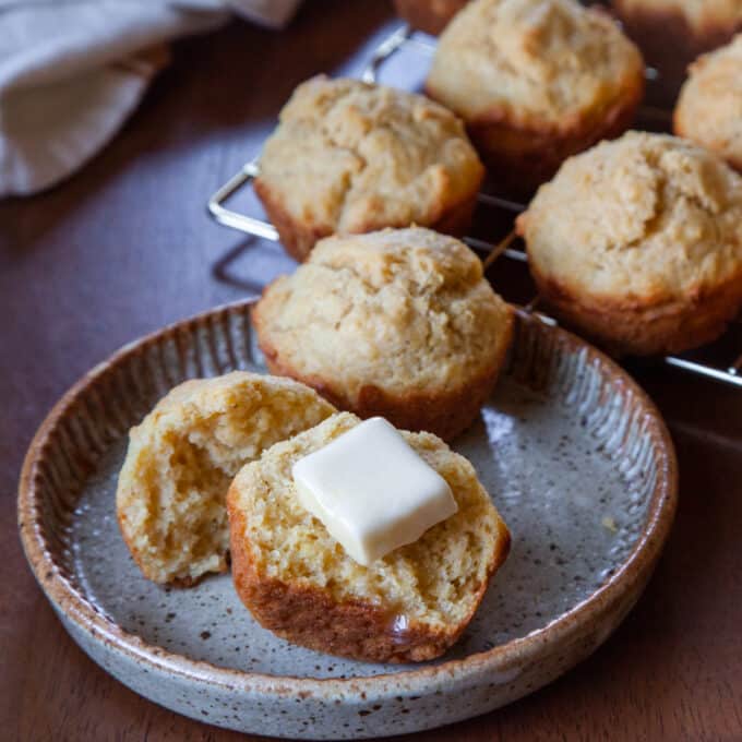 Cornbread muffins, one in half with a pat of butter.