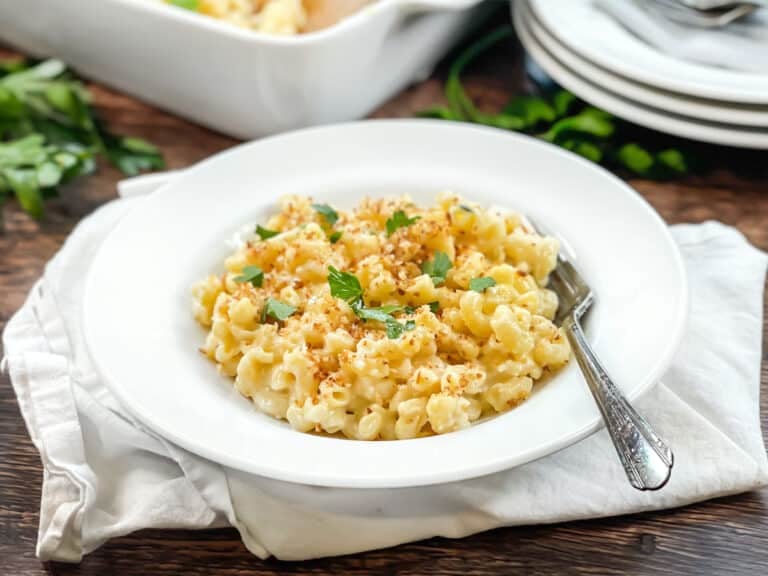White dish of macaroni and cheese topped with breadcrumbs and parsley.