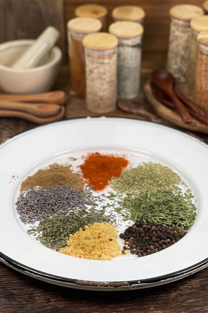 Various spices on a white plate with spice jars in the background.
