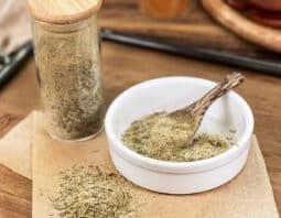 Turkey seasoning blend in glass jar, in dish with spoon, and spilled on parchment paper.