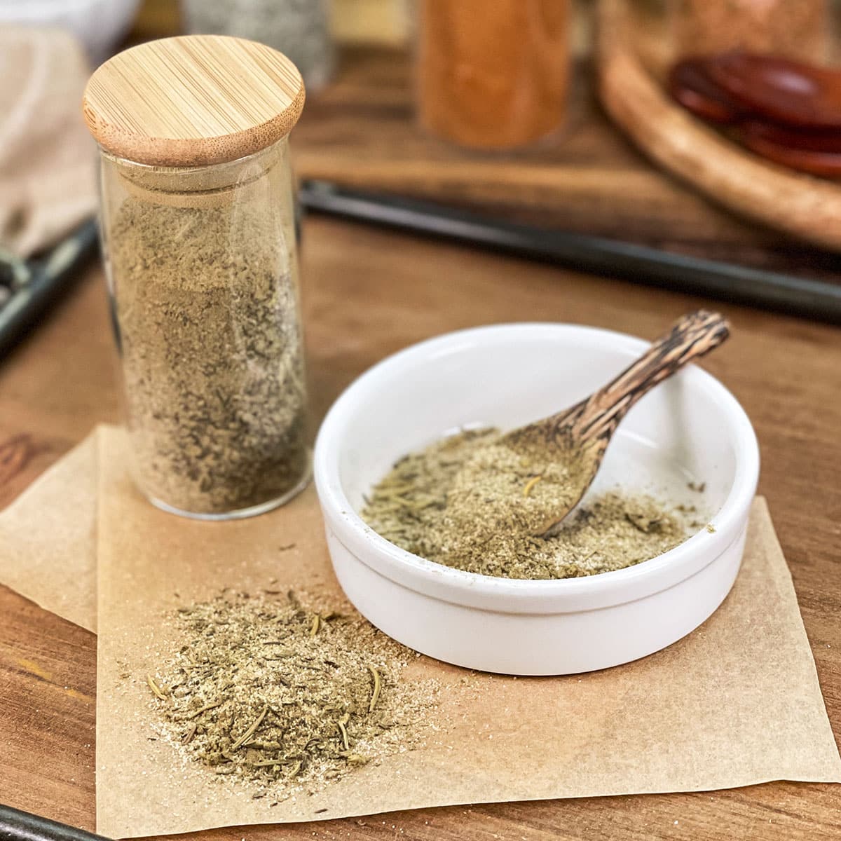 Turkey seasoning blend in glass jar, in dish with spoon, and spilled on parchment paper.