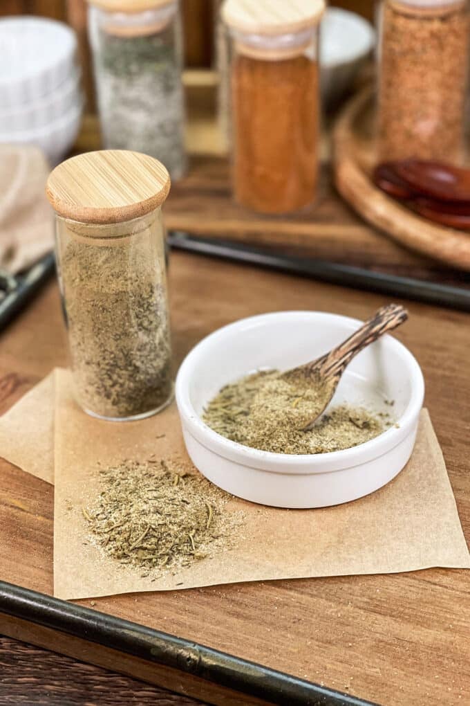 Turkey seasoning blend in glass jar, in dish with spoon, and spilled on parchment paper.