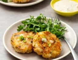 Fried fish cakes on a plate with salad greens.