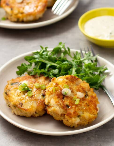 Fried fish cakes on a plate with salad greens.