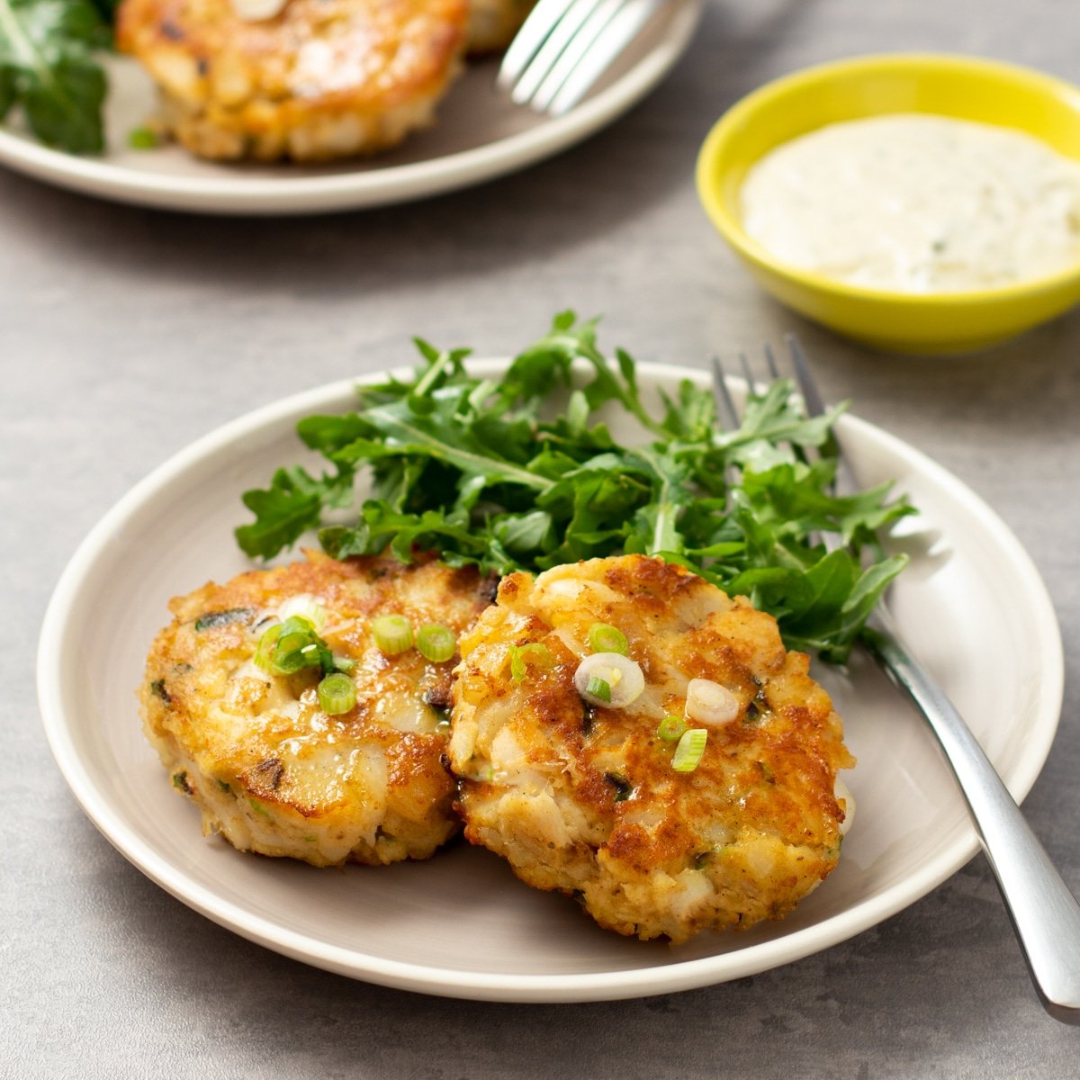 Fried fish cakes on a plate with salad greens.