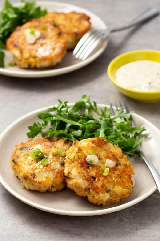 Fried fish cakes on a plate with salad greens.