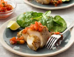 Grilled fish on plate with tomato salsa and salad greens.