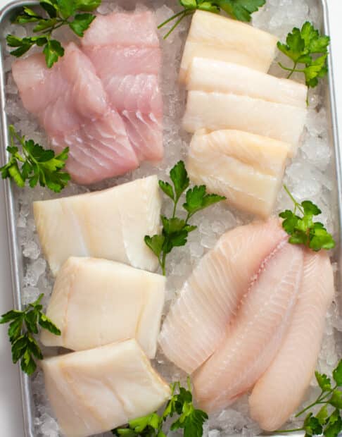 Various raw fish fillets on a tray of ice.