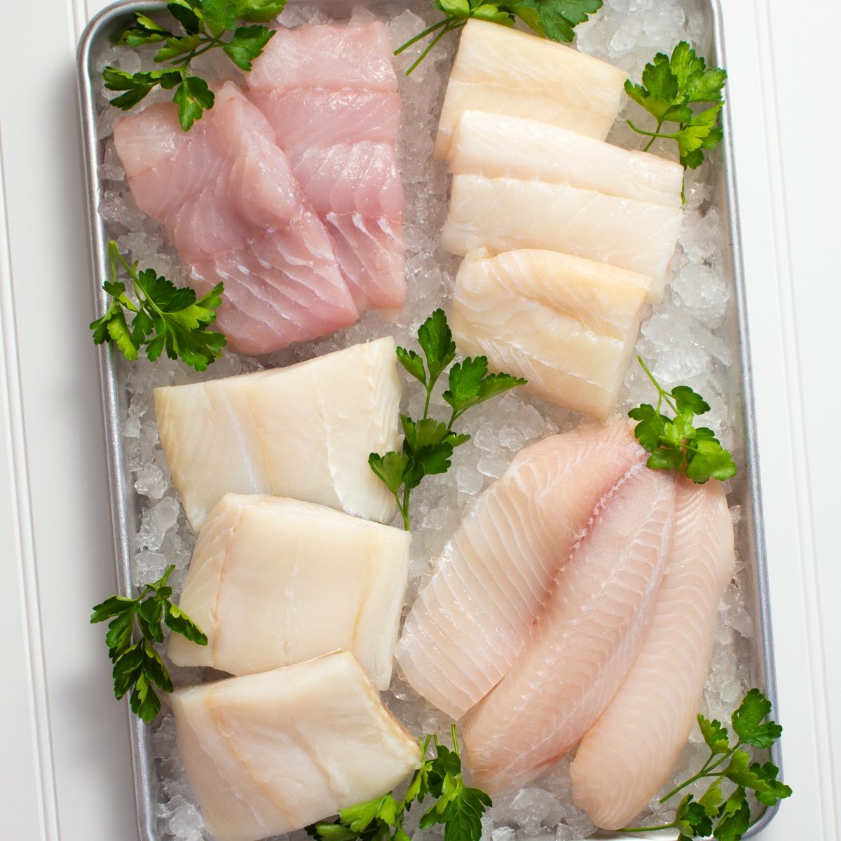 Various raw fish fillets on a tray of ice.