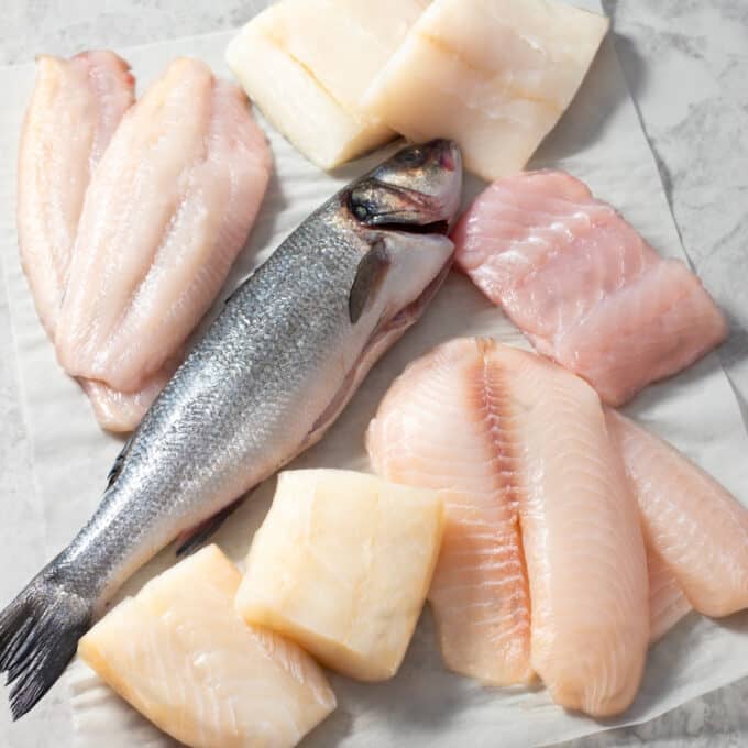 Various types of fish fillets and a whole raw fish.
