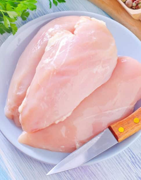 raw chicken breasts on a white plate