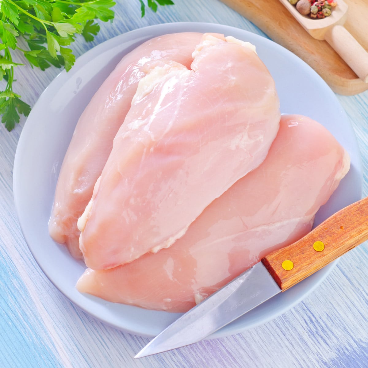 raw chicken breasts on a white plate