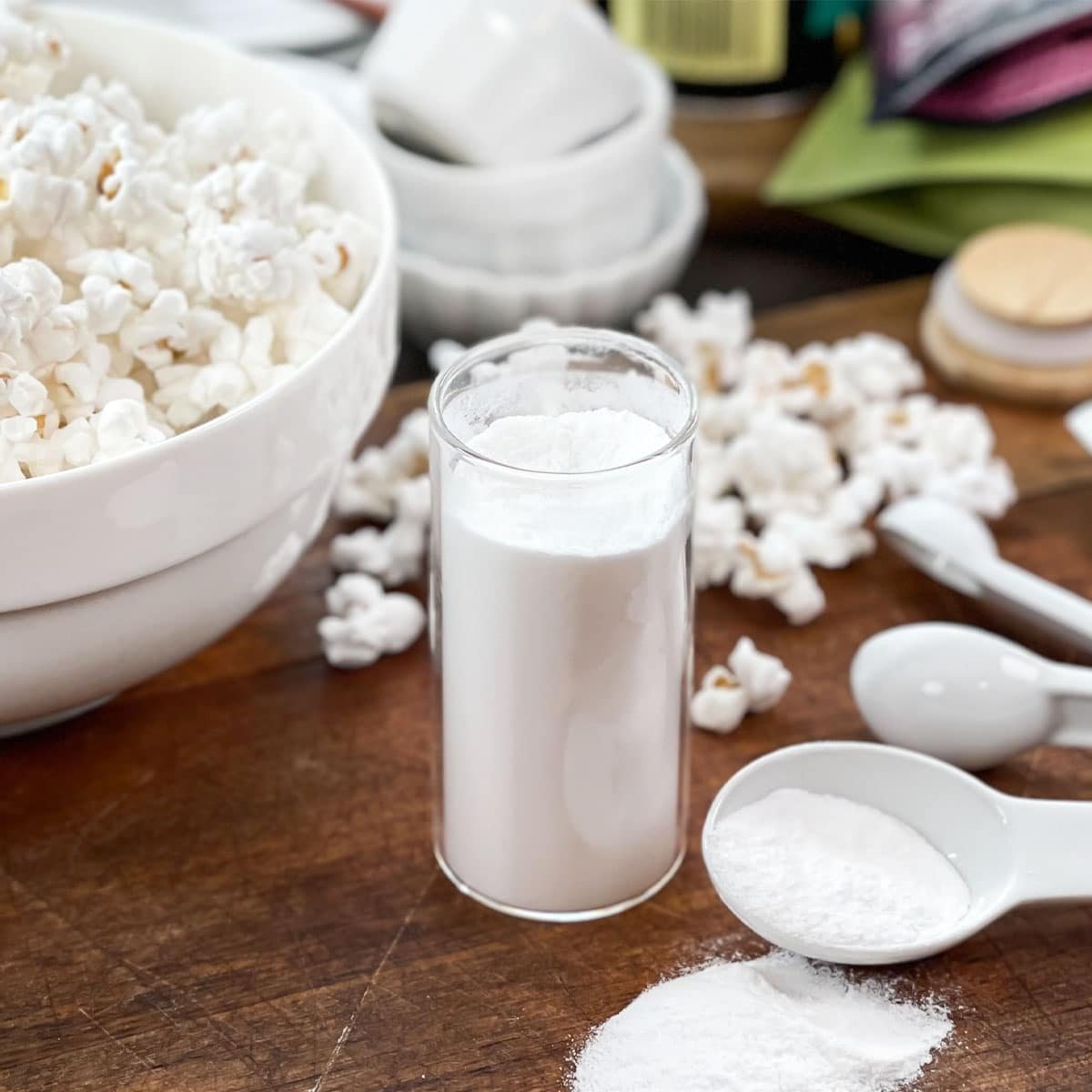 Spice jar of salt and vinegar seasoning, popcorn and measuring spoons around.