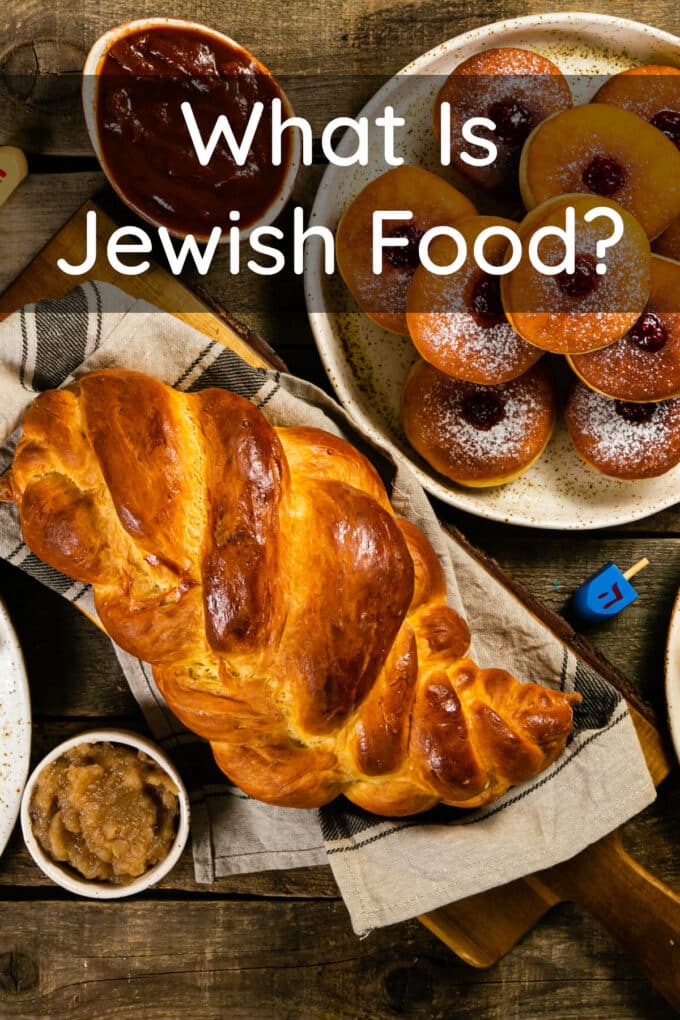 Challah bread, jelly doughnuts, and more on a wooden table, text reads What Is Jewish Food?