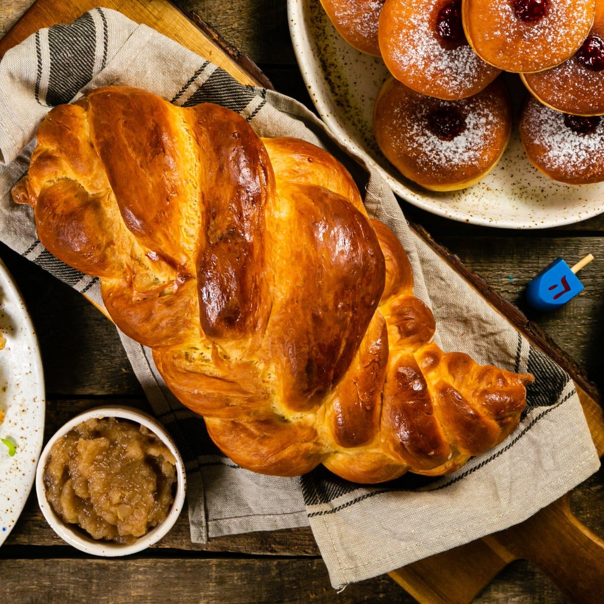 Challah and other Jewish foods on a wooden table.