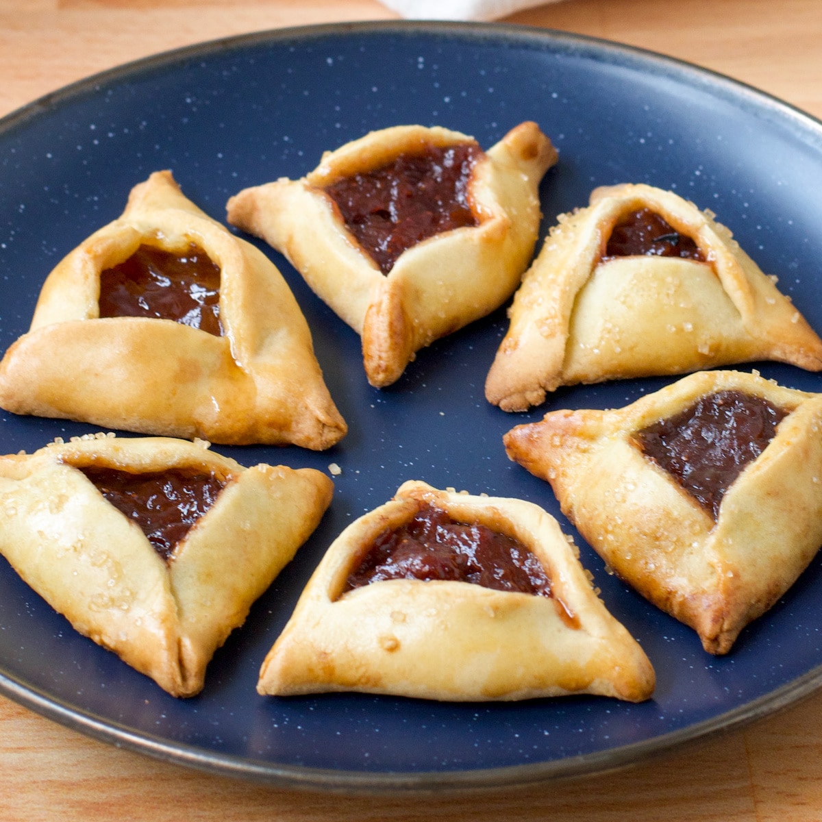 Hamantaschen, jam filled triangular cookies, on a blue plate.