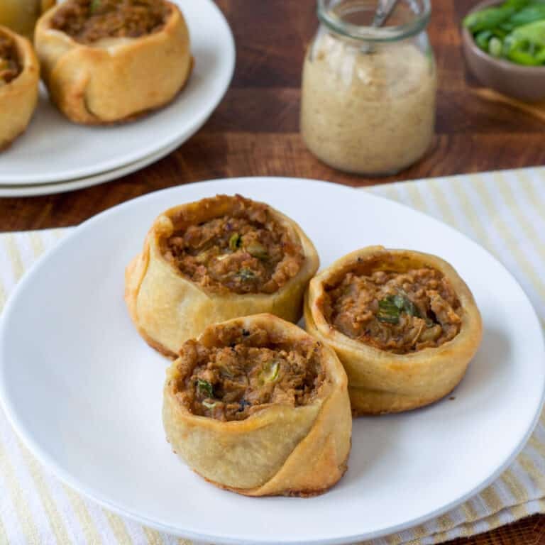 Three potato knish on a white plate.