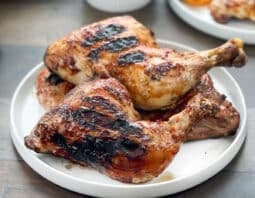 BBQ grilled chicken legs on a white platter.
