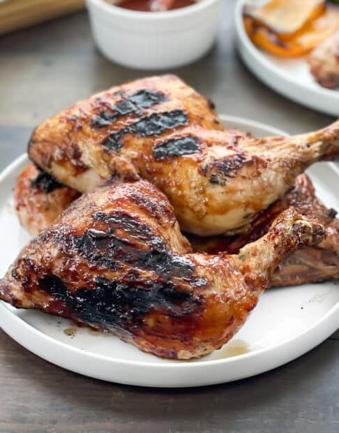 BBQ grilled chicken legs on a white platter.