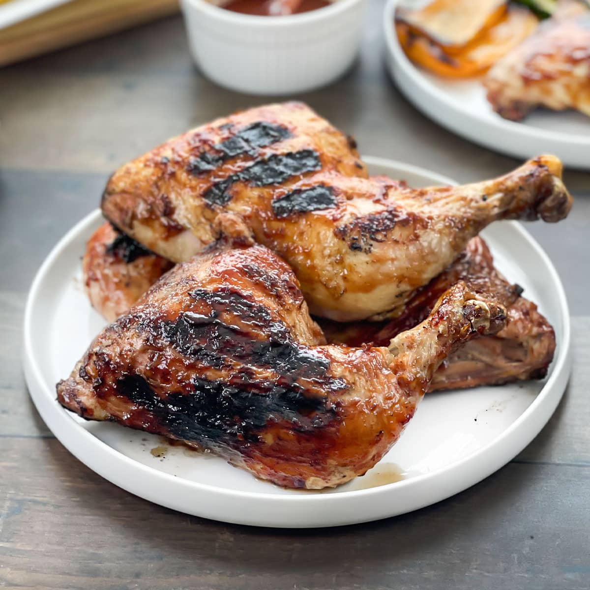 BBQ grilled chicken legs on a white platter.