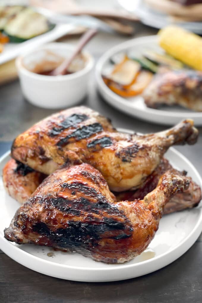 BBQ grilled chicken legs on a white platter.