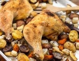 Chicken leg quarters and root vegetables on a sheet pan.