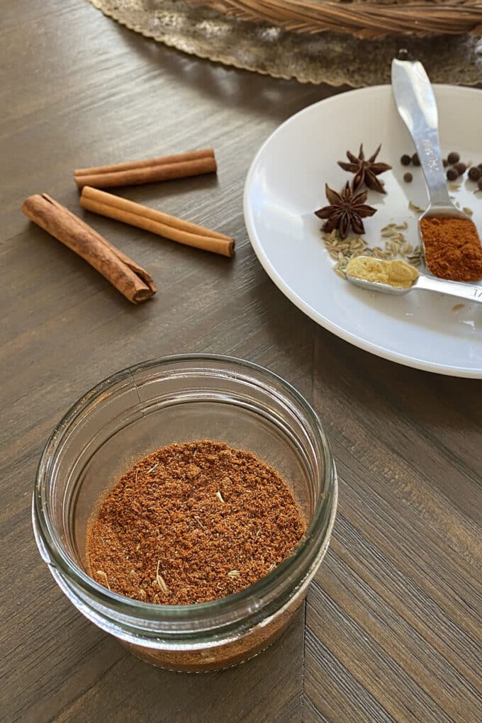 Pepperoni seasoning blend in glass jar with spices in background.