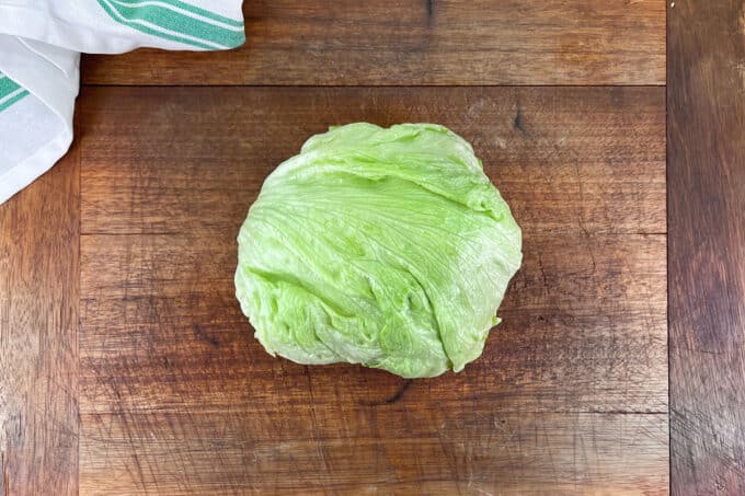 Head of iceberg lettuce on wooden board.