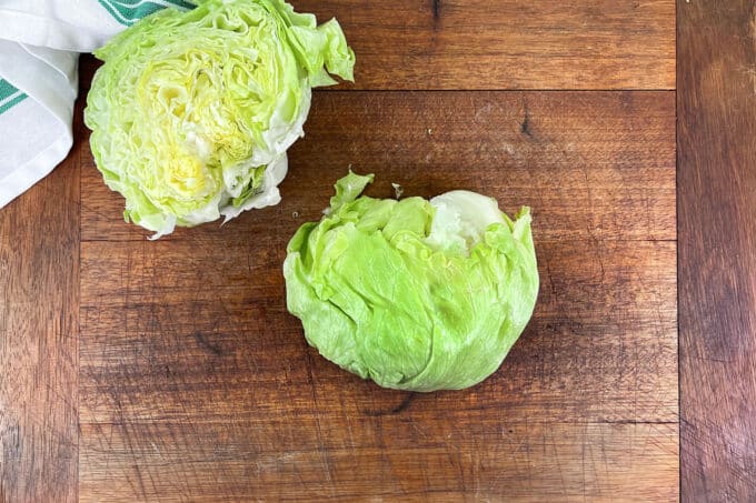 Halved head of lettuce on cutting board.