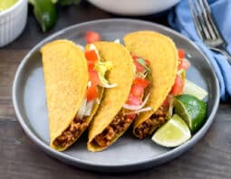 Ground turkey tacos with tomato and lettuce, lime wedges on side.