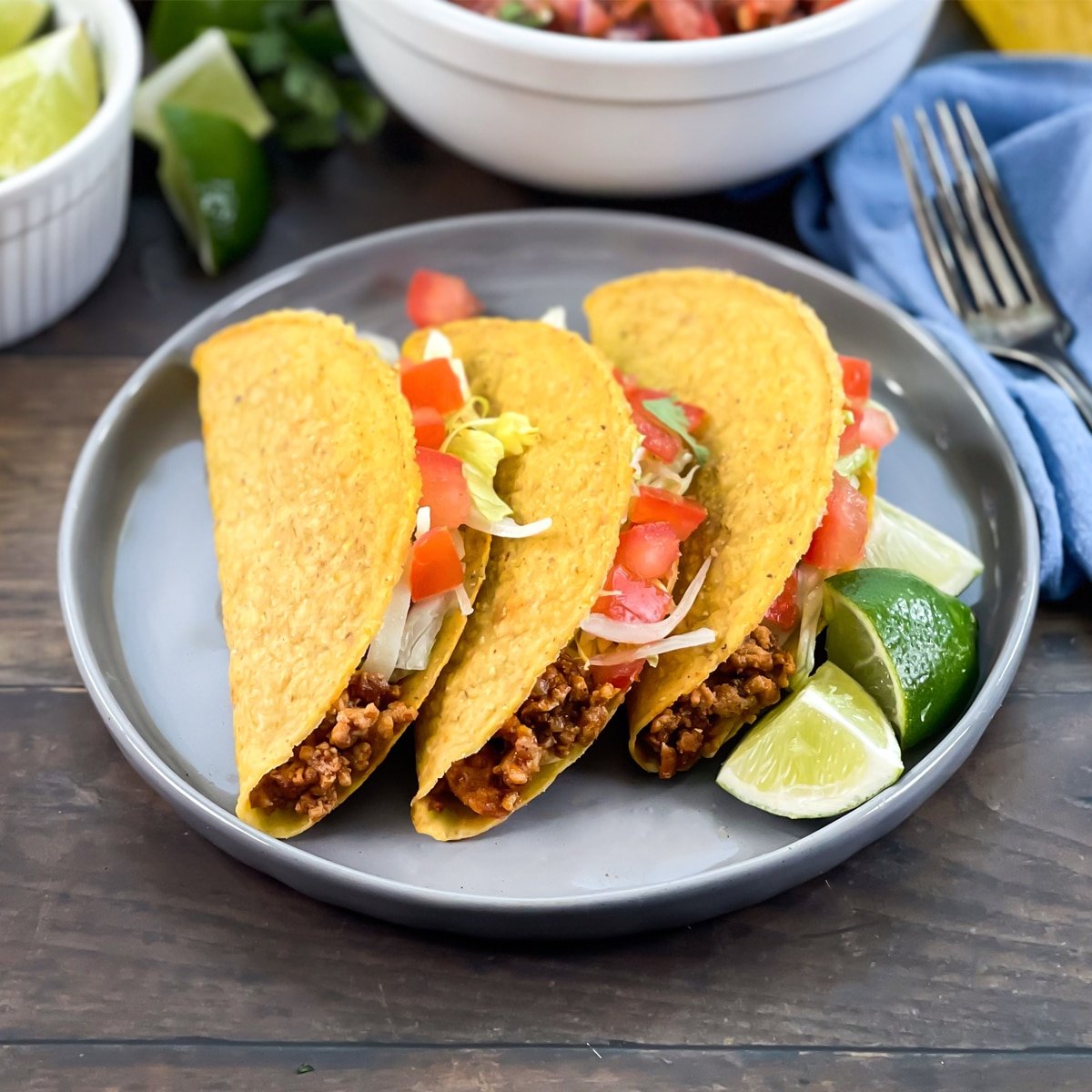 Ground turkey tacos with tomato and lettuce, lime wedges on side.