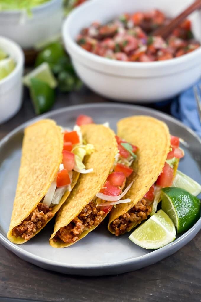 Ground turkey tacos with tomato and lettuce, lime wedges on side.