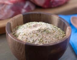 Wooden bowl with Santa Maria seasoning blend, raw beef in background.
