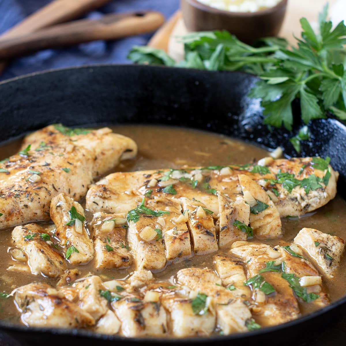 Sliced chicken breasts and garlic butter sauce in skillet.