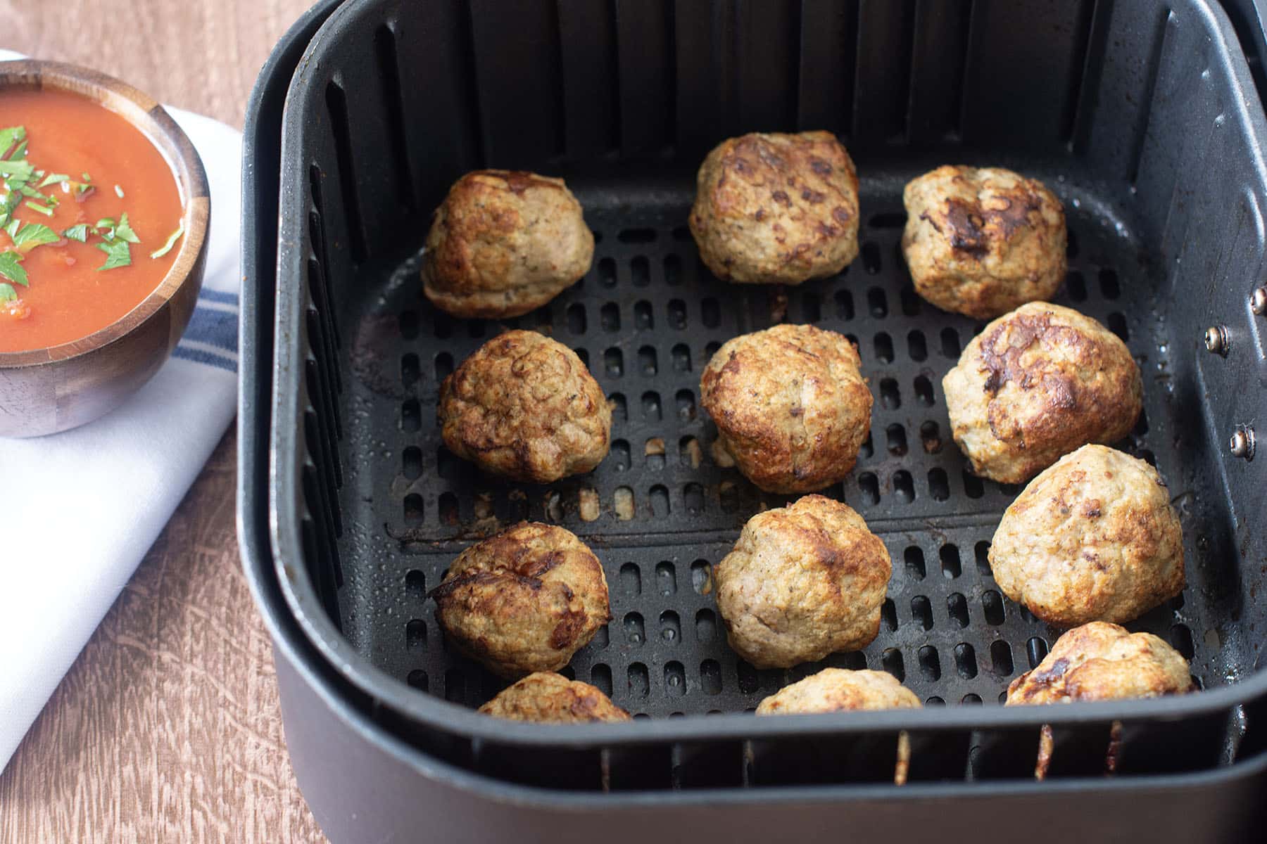 Cooked turkey meatballs in the air fryer basket.
