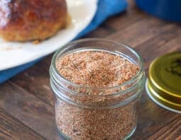Meatloaf seasoning mix in a glass jar with meatloaf in background.