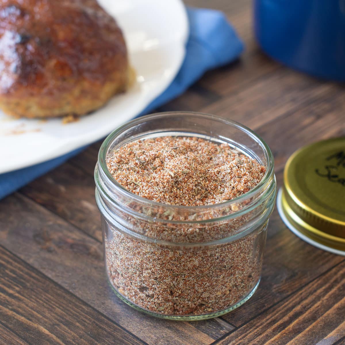 Meatloaf seasoning mix in a glass jar with meatloaf in background.