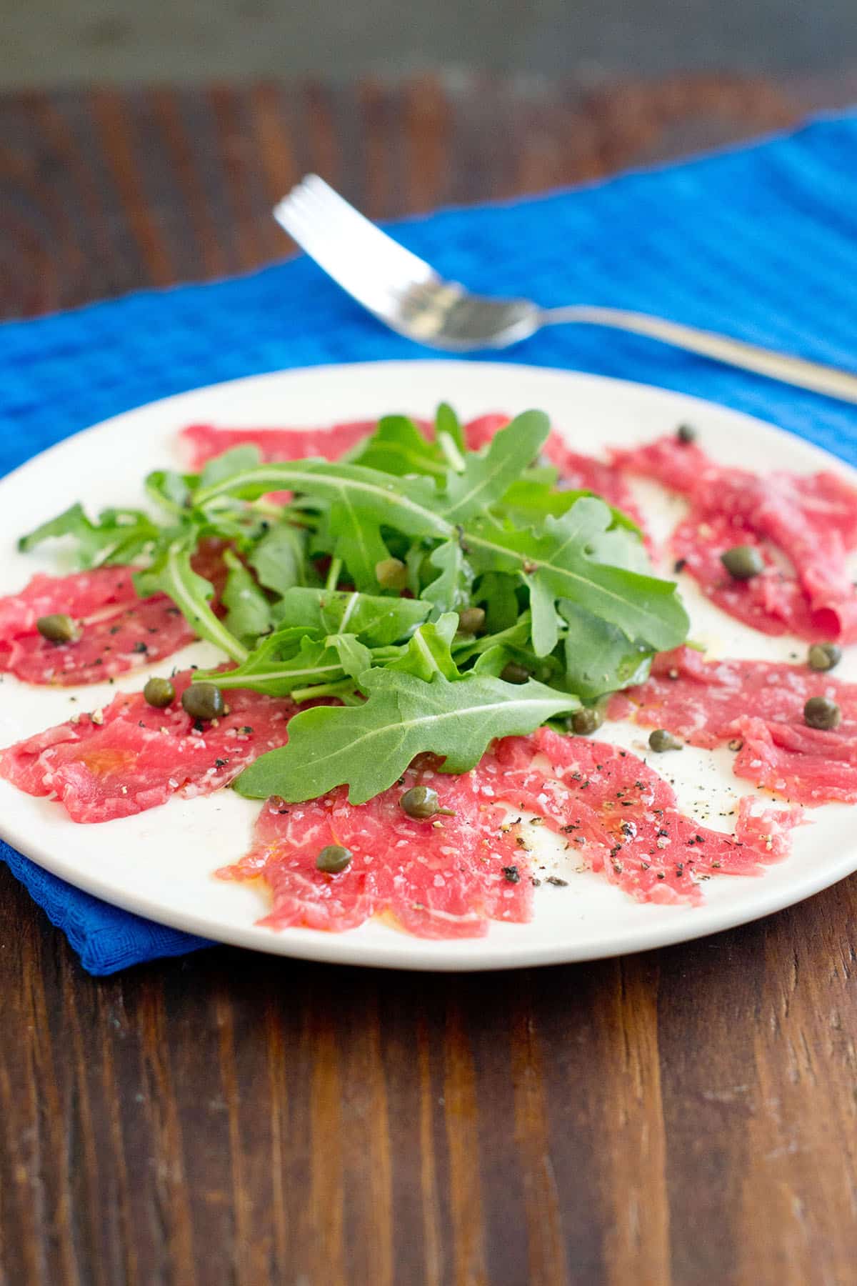 Beef carpaccio Beef carpaccio with arugula and capers on a white plate.