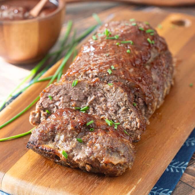 Beef meatloaf on a cutting board with a couple slices cut.