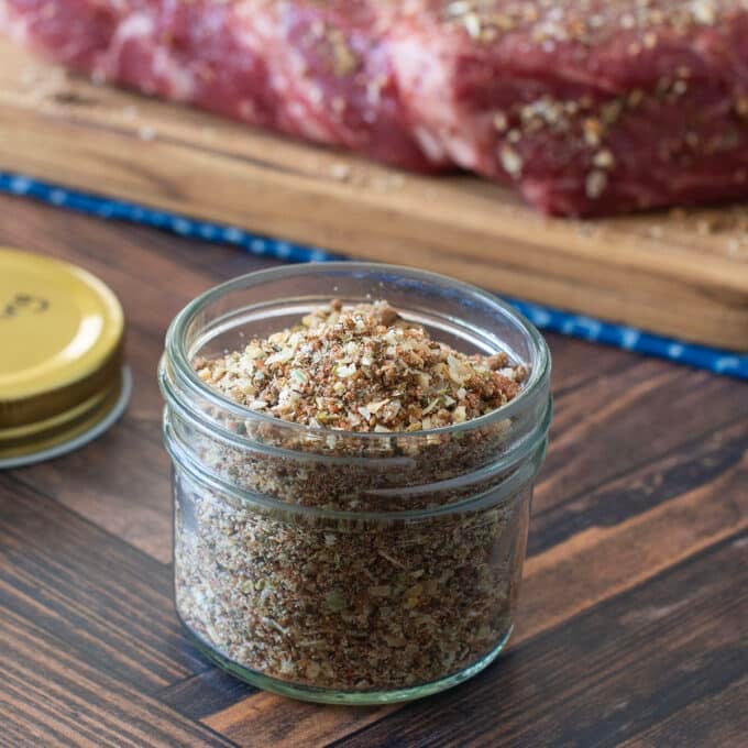 Glass jar with homemade pot roast seasoning, raw roast in background.