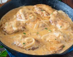 Pan of chicken thighs in a creamy onion gravy.