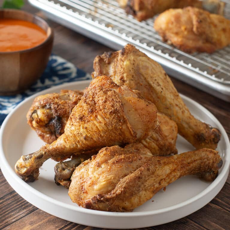 Light gray plate with pile of crispy baked chicken drumsticks.